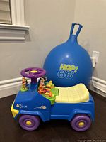 Blue Winnie The Pooh-themed ride-on car with purple wheels and steering wheel, yellow cushioned seat, and Winnie The Pooh characters on dashboard and body.