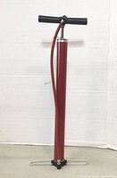 Front view of the 18-inch red manual automotive hand pump with black T-handle and red hose.