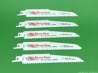 Five ToolTech Xpert reciprocating saw blades arranged side by side on a green surface.