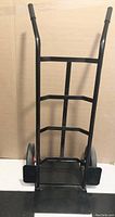 Front view of black metal heavy duty hand truck with ergonomic rubber handle grips and ladder-style frame