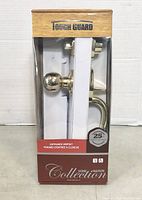 Front view of Tough Guard entrance gripset box showing door knobs and lever handle in polished brass finish with 25-year warranty.
