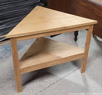 Photo of unfinished butternut wood triangular table showing its shape, two shelves, and natural wood grain