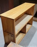 Angled view of the wooden shelf showing side panel and three open compartments.