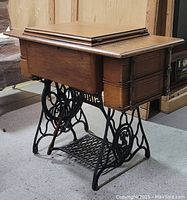 Closed view of Singer treadle sewing machine cabinet with wooden top closed.
