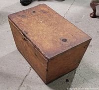 Closed antique wooden chest placed on a concrete floor showing overall exterior and finish.