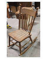 Wooden rocking chair with slabbed seat and pressed backrest. Chair is placed indoors with other furniture around.