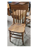 Full view of the wooden chair showing pressed back design, vertical spindles, and wooden seat.