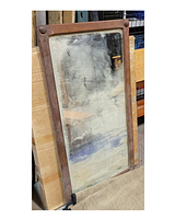 Photo of tall rectangular antique wall mirror with wooden frame and aged glass showing spots and cloudiness.