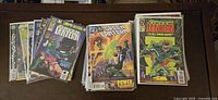 Photo showing three stacks of Green Lantern comics, with some covers visible including issue 50, showing detailed superhero artwork and title branding.