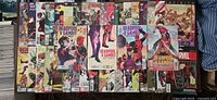 Photo shows a spread of Deadpool comic books arranged in rows, featuring various issues including Deadpool v. Gambit and other titles, colorful covers with Marvel branding.