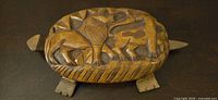 Top view showing detailed relief carving of lion and other animals on the turtle shell lid.