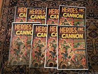 Full set of eight 'Heroes Inc. Presents Cannon' comic books arranged on a patterned carpet. Covers feature colorful illustrations and the title prominently along with various character images.