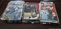 Top view of three separate stacks of Punisher comic books in protective sleeves, arranged on a brown table showing various cover arts.