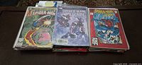 Three stacks of Marvel Spider-Man comic books laid out showing various cover art and titles