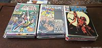 Three stacks of Marvel comic books featuring Wolverine and related characters, showing variety of titles and cover art.
