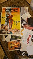 Two different movie posters for 'International Counterfeiters' arranged on floor with other papers and items partially covering them.