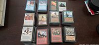 Multiple stacks of Magic the Gathering cards arranged on table showing various colors and cards faces.