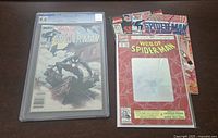 Web of Spider-Man #1 CGC 9.0 comic in protective casing with other Spider-Man comics stacked beside it on table
