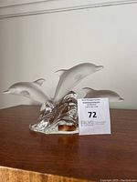 Full front view of the dolphin paperweight on wood surface with auction tag.