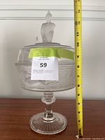 Full view of the clear glass covered compote with measuring tape showing height approx. 13 inches.