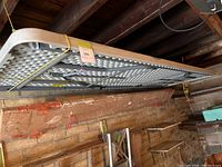 Side view of foldable table hanging from ceiling with a yellow rope. Showing underside of table.