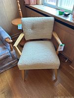 Front view of cream bouclé armchair showing upholstered seat and backrest with light wood frame and tapered legs