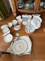 Full view of the 12-piece china set including plates in quilted fabric cases and smaller plates stacked separately.