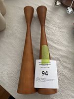 Pair of teak wood candlesticks shown with auction label.