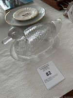 Side view of clear pressed glass duck on nest candy dish showing textured details and shape.