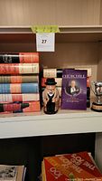 Photo showing stack of hardcover books with titles related to Winston Churchill and history, along with ceramic figurine and trophy cup.