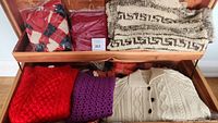 Wide shot showing all wool sweaters in the lot arranged in a drawer or chest, various styles and colors visible.