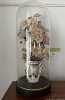 Side angle view showing ornate gold-accented vase inside the glass dome.