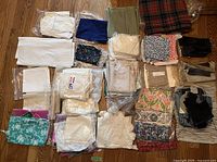 Top-down view of assorted folded and packaged fabric pieces in various colors and prints arranged on wooden floor.
