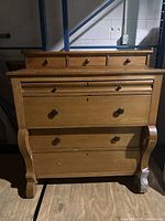 Front view of antique pine Empire dresser chest of drawers showing all drawers and curved legs, with front right leg damaged.