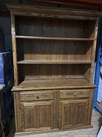 Full view of the oak cupboard cabinet showing open shelving, drawers and doors below.