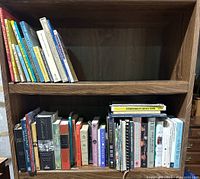 Photo showing two shelves filled with an assortment of books including children's books, thick hardcover Bibles, and various other books arranged side by side.