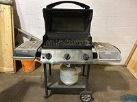 Front view of Napoleon Ultra Chef propane BBQ grill with lid open, showing three control knobs and propane tank below on wheeled stand.