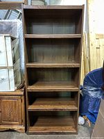 Front view of tall bookshelf with oak grain finish showing five shelves.