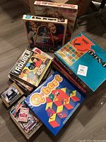 Vintage board games arranged on a floor showing their boxes and titles including Trouble and Q*bert