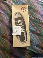 Brown Converse box featuring an image of a black Converse sneaker on the lid.