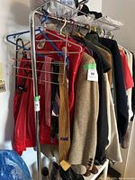 Metal clothing rack with various clothes hanging on it, shown from an angled side view.
