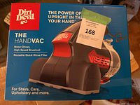 Front of box showing Dirt Devil Hand Vac vacuum cleaner, highlighting motor-driven high-speed brushroll and reusable quick-rinse filter for use on stairs, cars, upholstery, and more.
