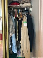 Side view of closet showing clothing items hanging and folded clothes on shelf.