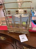 The full set showing three glass decanters labeled Bourbon, Rye, and Scotch in a gold-tone metal carrier with handle.