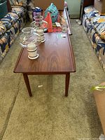 Table in living room setting with decorative accessories on top, showing top surface and legs