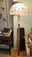 Full height view of the floor lamp showing twisted wooden stand, base and stained glass dome shade in room setting.
