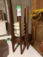 Front view of lamp showing four-post wooden frame and white ribbed shade