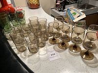 Photo showing 8 stemmed smoked glassware and 8 tumblers arranged on a table.