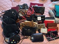 Full overview of assorted handbags and purses laid on bed showing variety of shapes, sizes, and colors.