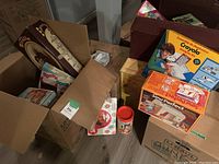 Photo showing multiple boxes of vintage kids toys including Speak & Spell, Crayola Drawing Kit, Sew Perfect sewing kit, Mirella doll box, and others packed in cardboard boxes.